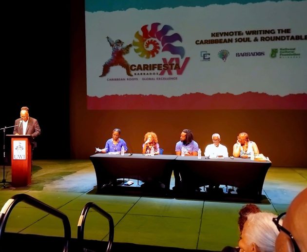 The master of ceremonies at the podium introduced the Carifesta XV Symposia panel, R–L: Bernice L. McFadden, U.S. novelist and professor; Lasana M. Sekou, St. Martin author and publisher; Marlon James, U.S.- based Jamaican novelist; Nancy Morejón, internationally acclaimed Cuban poet; and moderator Lafleur Cockburn of St. Vincent & the Grenadines. (Photo courtesy Sandra Sealy)